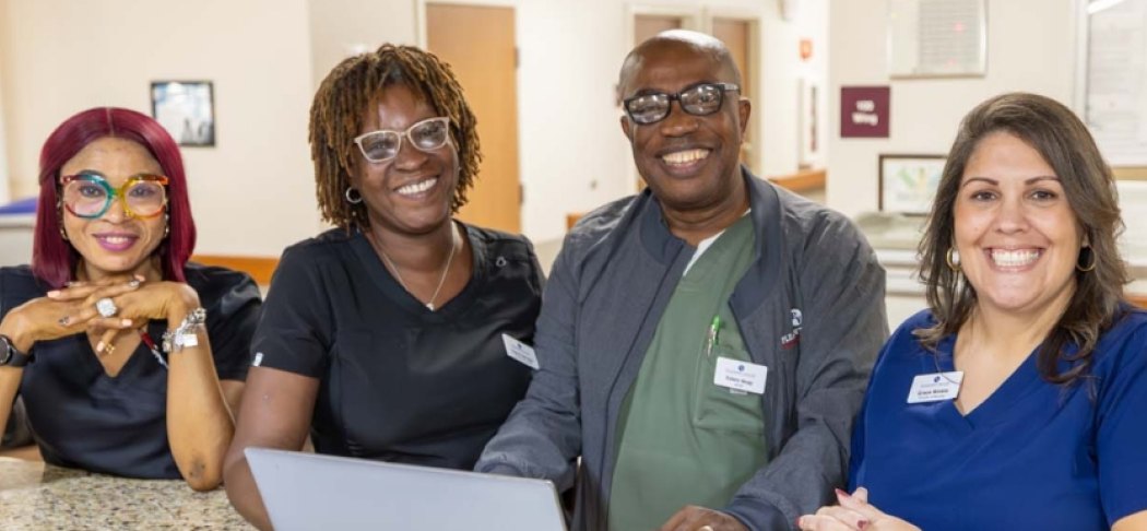 Four smiling care team members at a nurses’ station