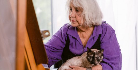 Resident painting at an easel with her cat on her lap